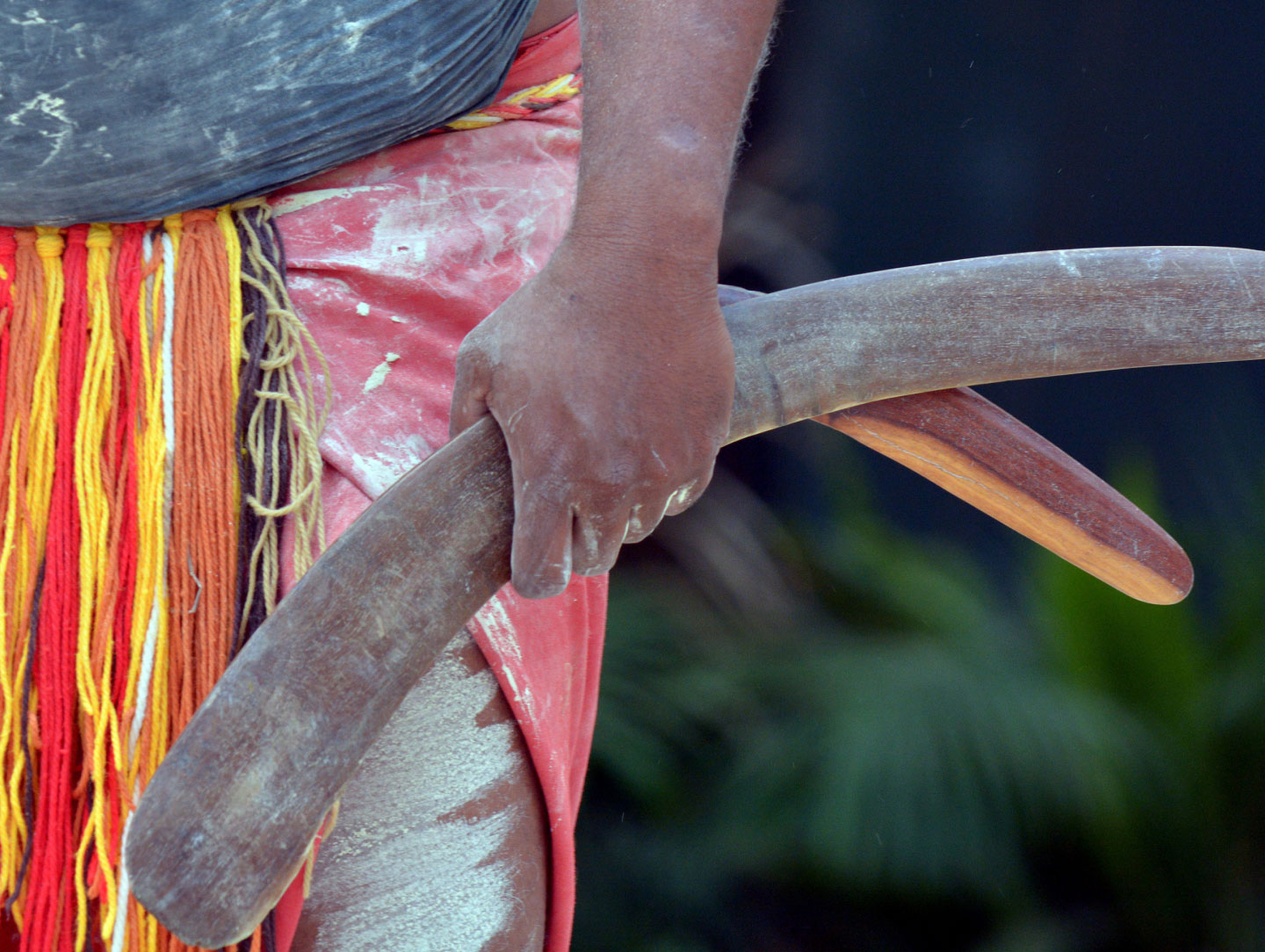 A hand of a First Nations person holding 2 boomerangs
