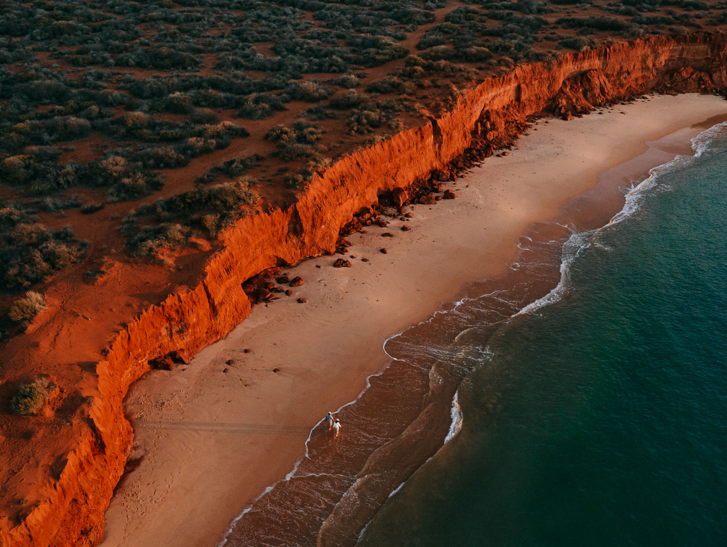 Outback red cliffs adjoin a beach